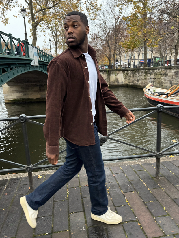 Man in cream knit polo walking past a Haussmann facade in Paris - Beaulin Paris