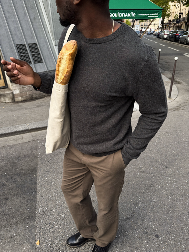 Man in charcoal knit with a canvas tote outside a Paris bakery - Beaulin Paris